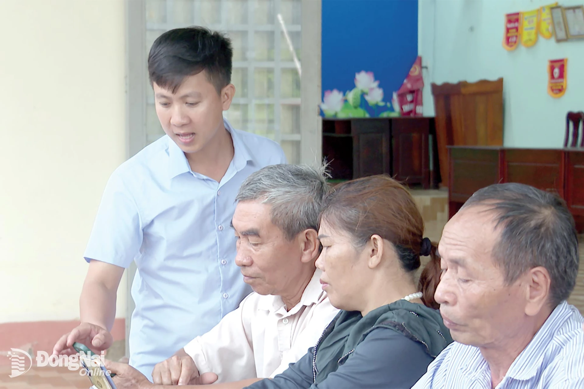Đảng viên Trần Văn Lộc, Trưởng thôn Thanh Xuân, xã Thiện Hưng hướng dẫn người dân cài đặt phần mềm trên điện thoại thông minh. Ảnh: Đặng Hùng