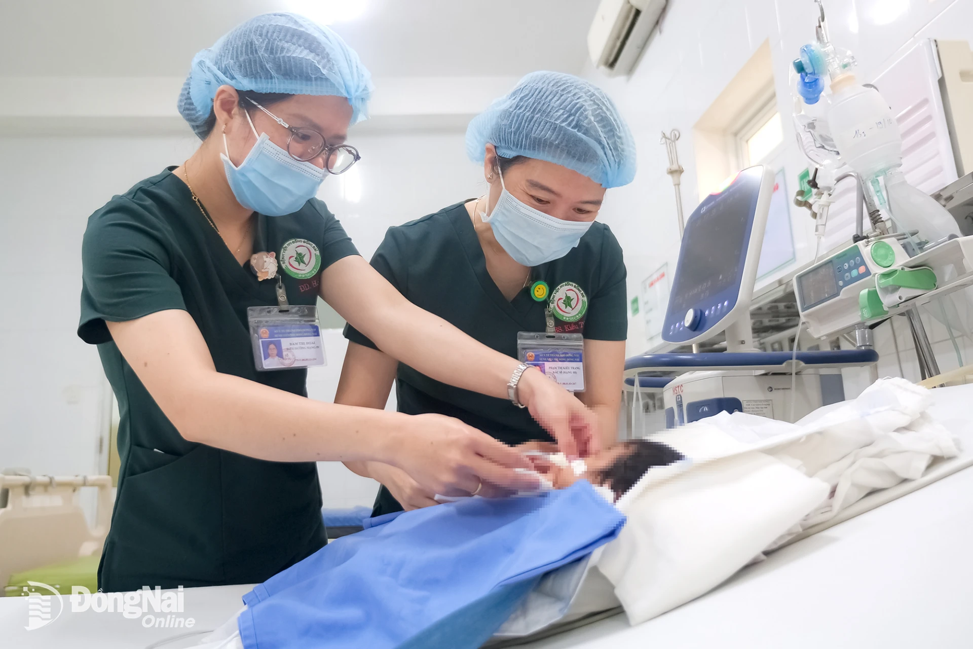 Điều dưỡng Đàm Thị Hoài (trái) và bác sĩ Phạm Thị Kiều Trang chăm sóc, thăm khám cho bệnh nhi.

