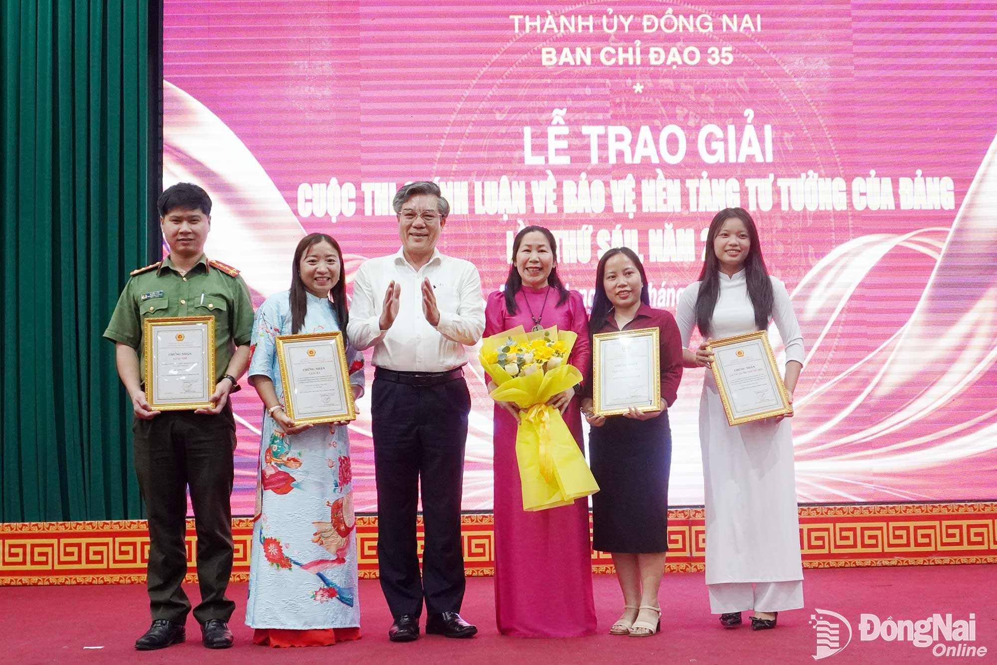 Ủy viên Ban Thường vụ Thành ủy, Trưởng ban Tuyên giáo Thành ủy Dương Minh Dũng chúc mừng em Lê Hoàng Thụy Phúc (bìa phải), học sinh lớp 12A2, Trường THPT Ngô Sĩ Liên và cô giáo Lê Thị Ngân (thứ 2 từ trái qua) đoạt giải tại Cuộc thi Chính luận bảo vệ nền tảng tư tưởng của Đảng lần thứ sáu, năm 2026 trên địa bàn thành phố.