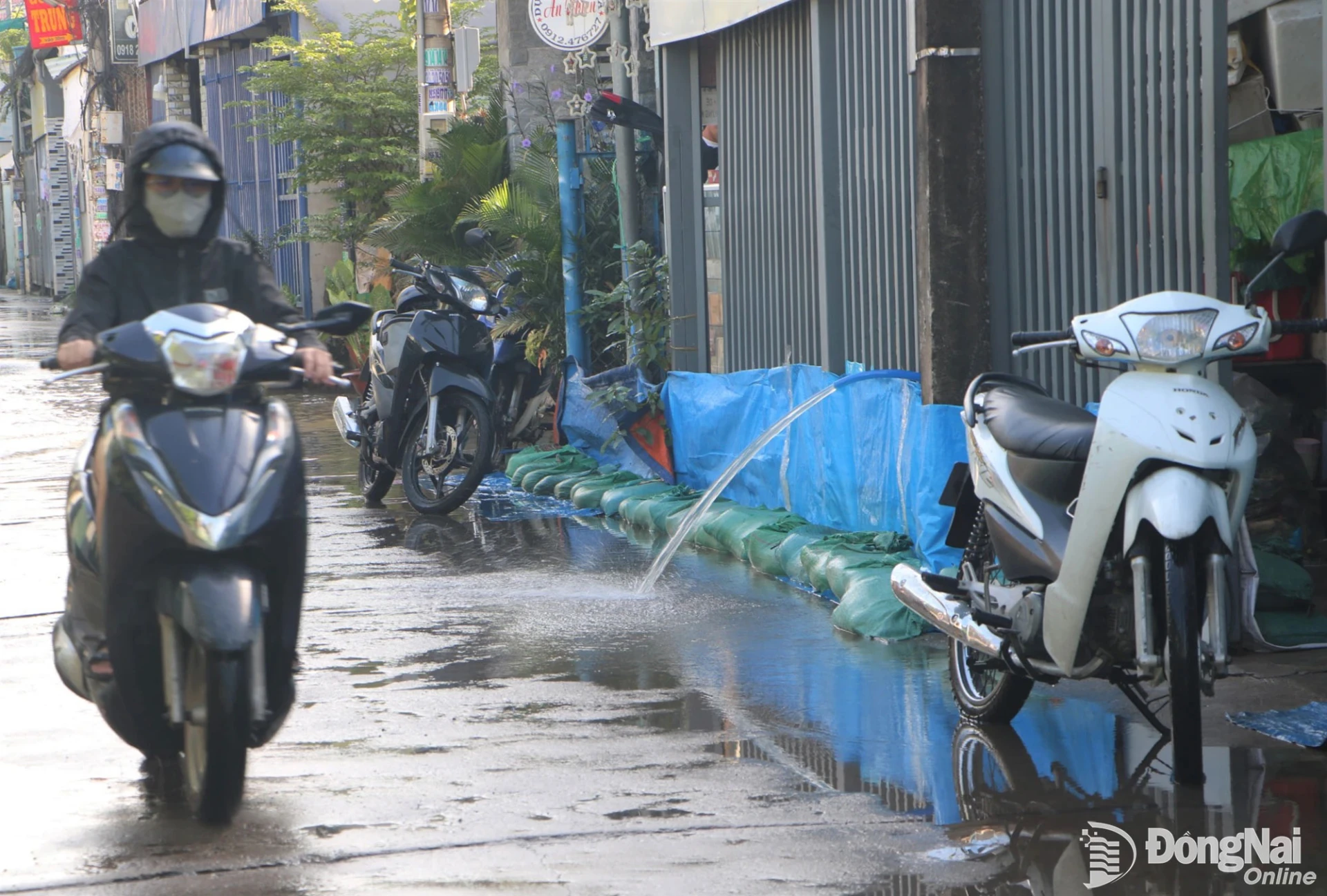 Một hộ dân ven đường Huỳnh Văn Hớn, khu phố Tân Mai, phường Tam Hiệp dùng bao tải cát đắp dọc hàng rào để ngăn nước tràn vào nhà. Ảnh: Phạm Tùng
