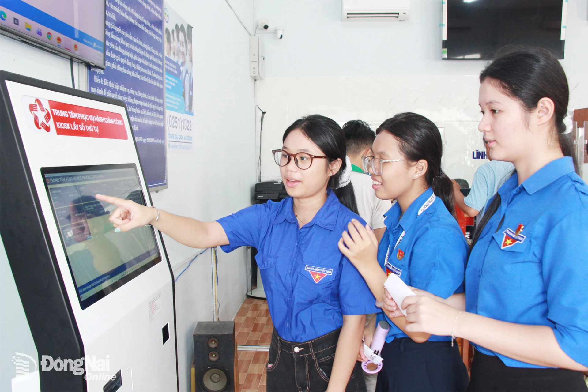 Đoàn viên, thanh niên phường Long Hưng chia sẻ cách sử dụng Kiosk lấy số thứ tự đặt tại Trung tâm phục vụ hành chính công của phường để cùng hỗ trợ người dân đến làm thủ tục hành chính. Ảnh: Nga Sơn
