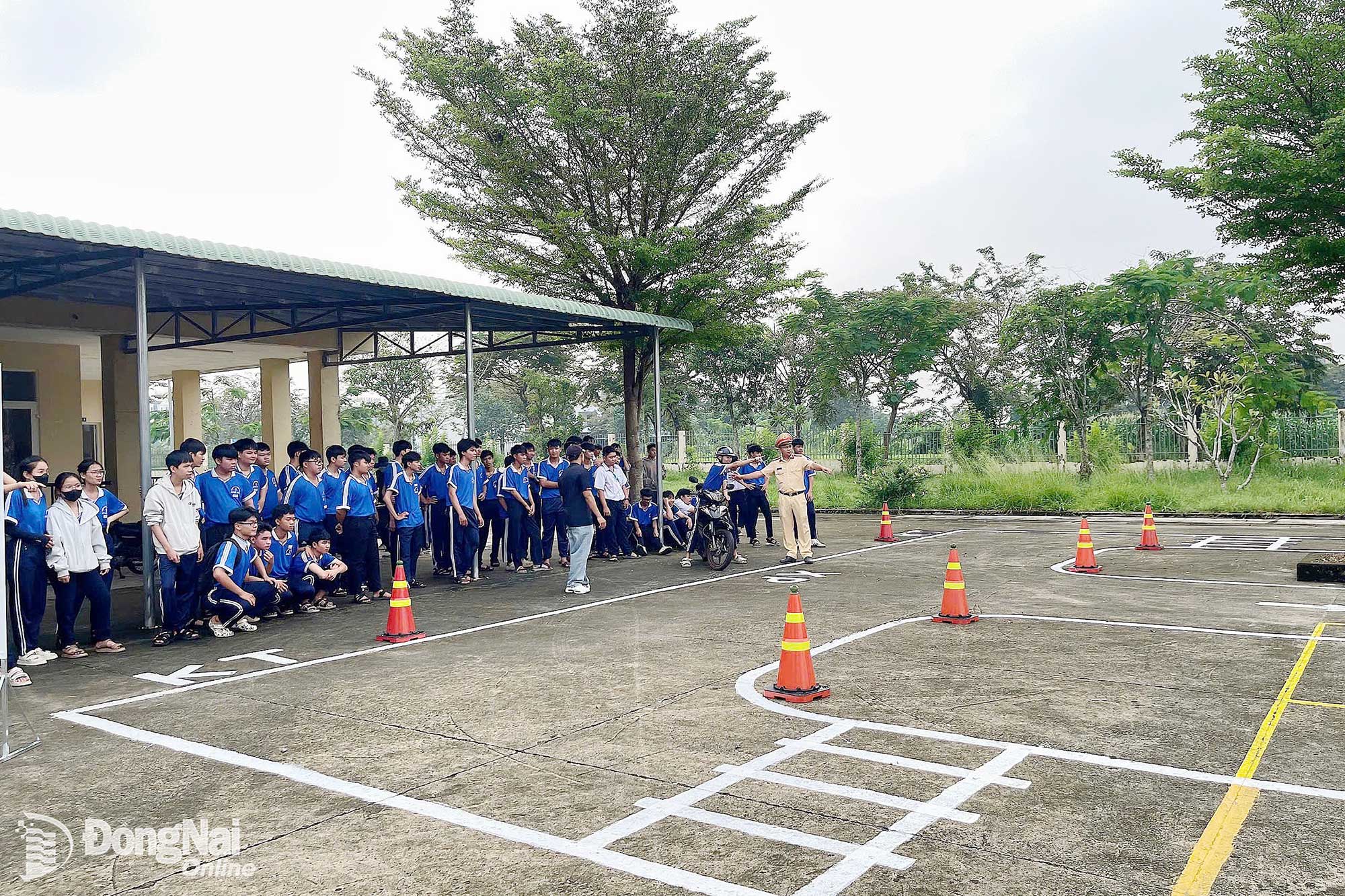 Cán bộ Trạm Cảnh sát giao thông ngã ba Thái Lan hướng dẫn học sinh Trường THPT Bình Sơn, phường Long Thành về sa hình 11 tình huống giao thông thực tế. Ảnh: Mộc Miên