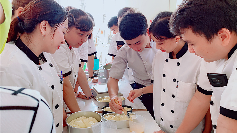 Anh Châu Vân Phi Long (giữa) đang truyền đạt kiến thức, kỹ năng làm bánh cho học viên