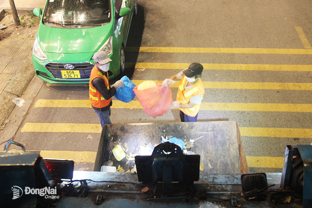 1.  Công nhân thu gom rác của Công ty CP Môi trường Sonadezi làm việc dưới ánh đèn đường