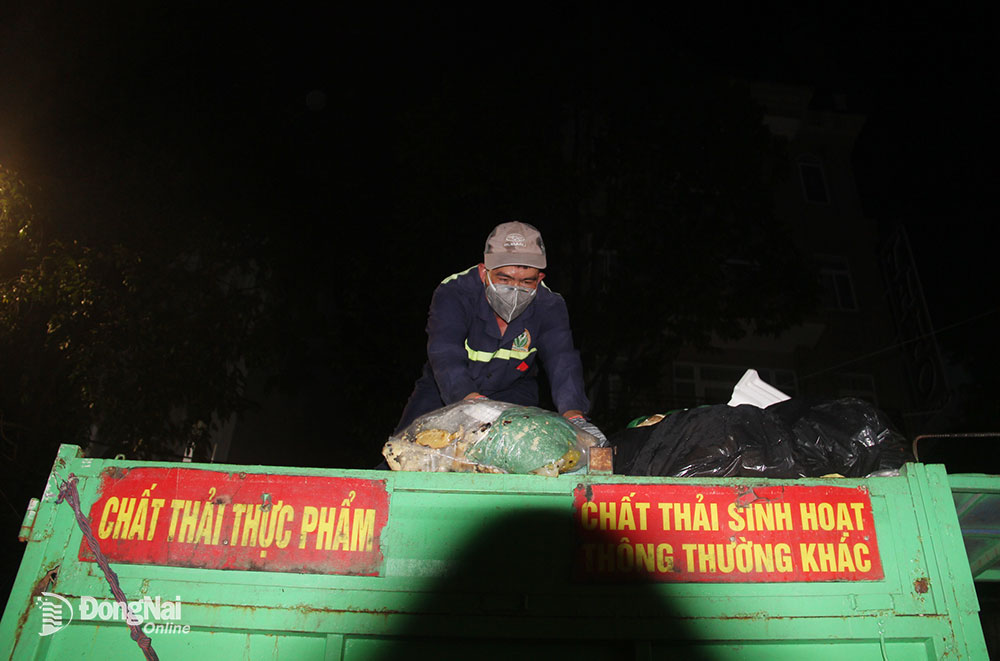 4.  Công nhân sắp xếp lại những bao rác được chất đầy trên các thùng xe chở rác
