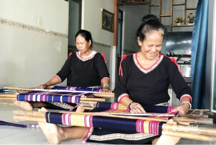 Thi Phot (right) and other women in the village weave brocade pieces with the vibrant colors of tradition and their love for the homeland.