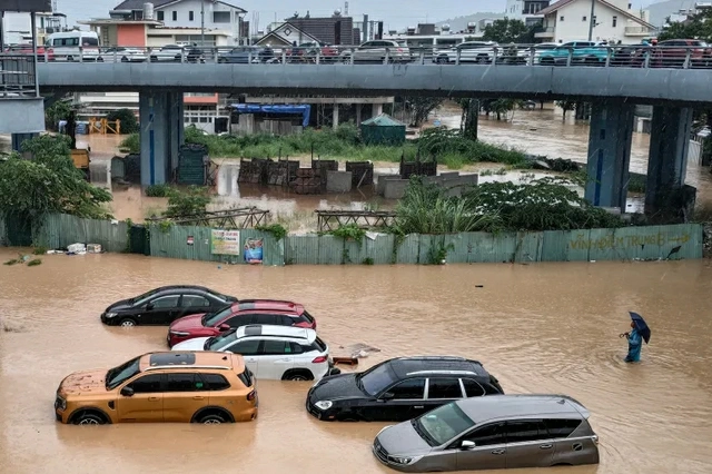 A man wades through floodwaters near inundated vehicles in Nha Trang, in Viet Nams coastal province of Khanh Hoa, on November 20, 2025
