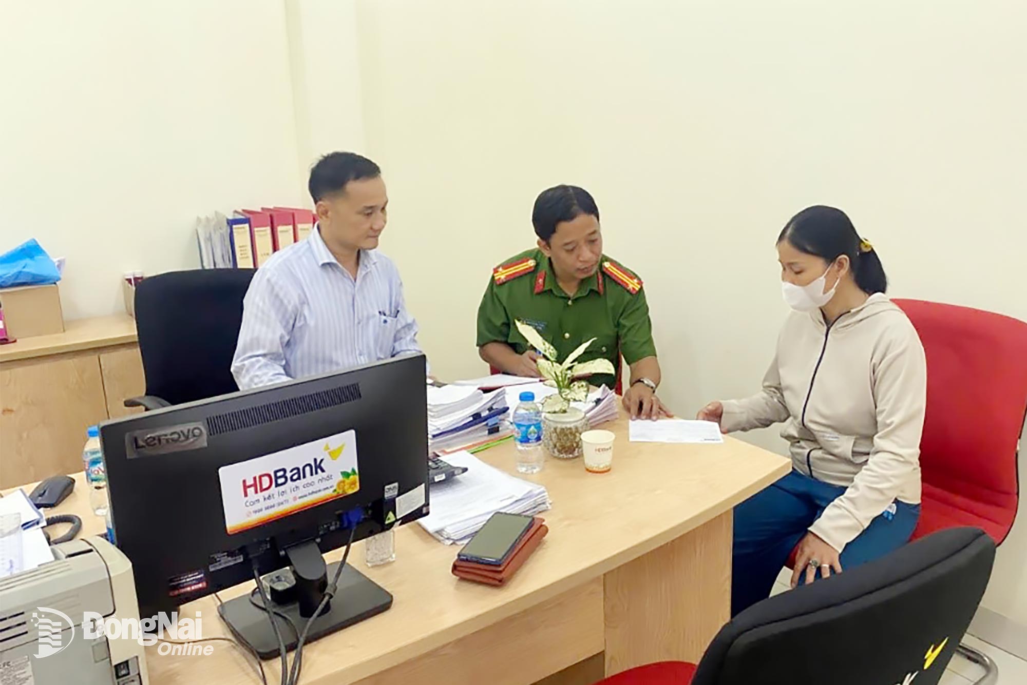 Cán bộ Công an phường Tam Phước và nhân viên ngân hàng tuyên truyền cho chị Ngoan. Ảnh: CAT