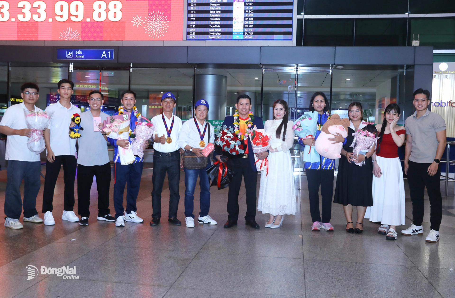Thành viên Đội tuyển Vovinam Đồng Nai, người thân chúc mừng thầy trò huấn luyện viên Huỳnh Minh Hải, Thị Lài, Nguyễn Mạnh Phi tại Sân bay Tân Sơn Nhất. Ảnh: Huy Anh