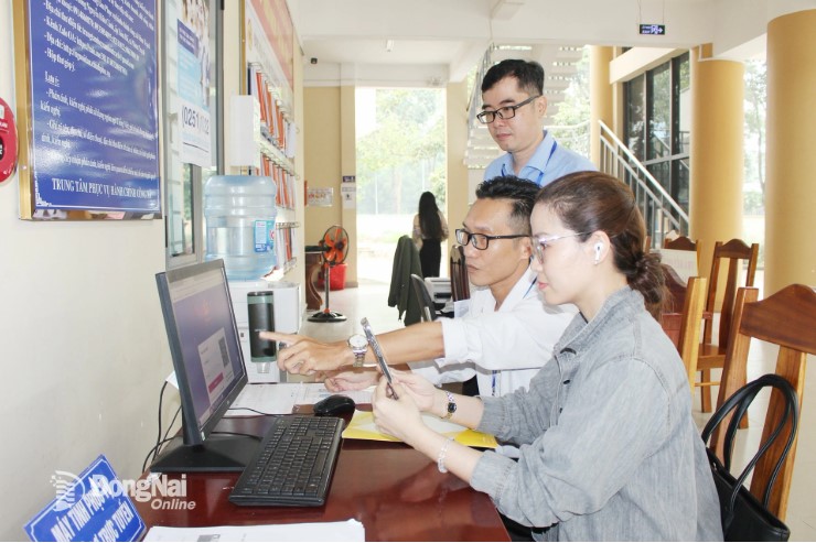 People are guided by commune officials and civil servants on online operations when they come to complete administrative procedures at Nhon Trach Commune Public Administration Service Center. Photo: Ho Thao