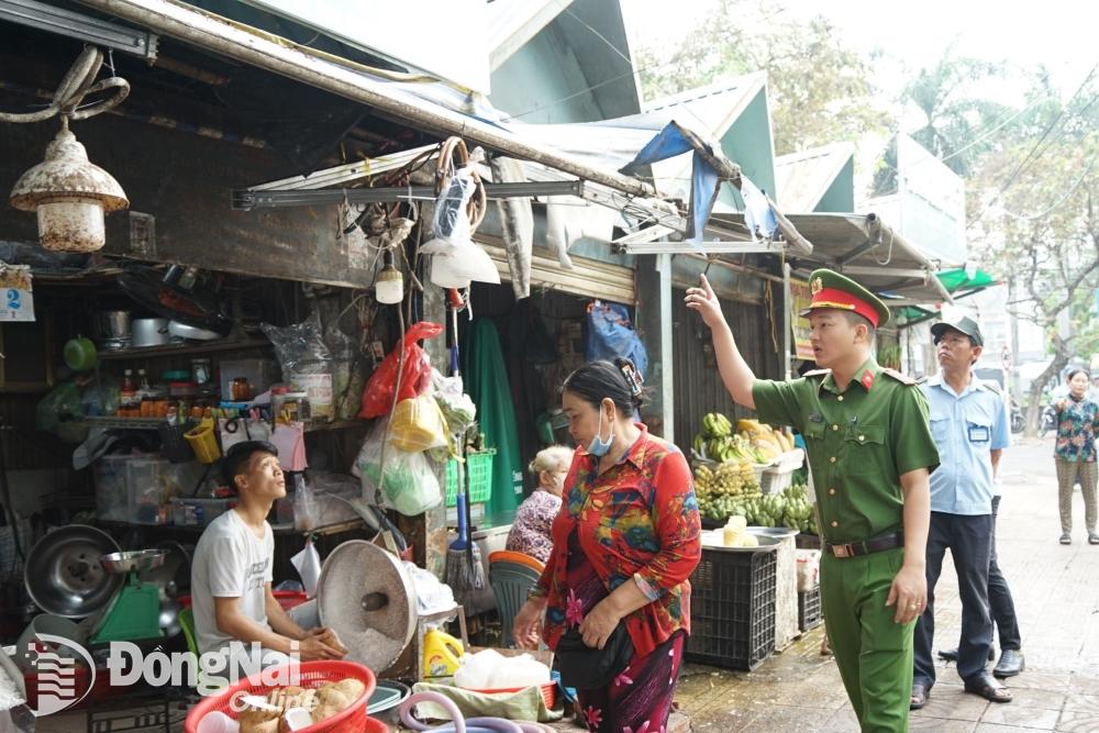 Công an phường Quang Vinh nhắc nhở các hộ tiểu thương thu dọn mái bạt trên đường Nguyễn Văn Trị. Ảnh: Lê Duy