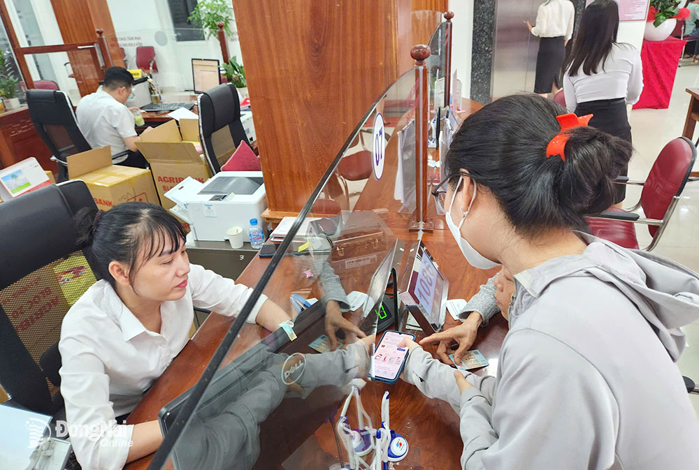 Nhân viên một chi nhánh ngân hàng ở thành phố Biên Hòa hỗ trợ khách hàng thực hiện xác thực sinh trắc học cho tài khoản ngân hàng. Ảnh: H.Quân