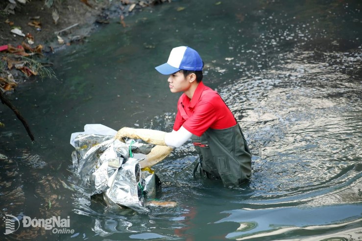 Gen Z Dang Minh Hieu shows no hesitation to wade through pitch-black water to collect trash. Photo: Thuy Tien