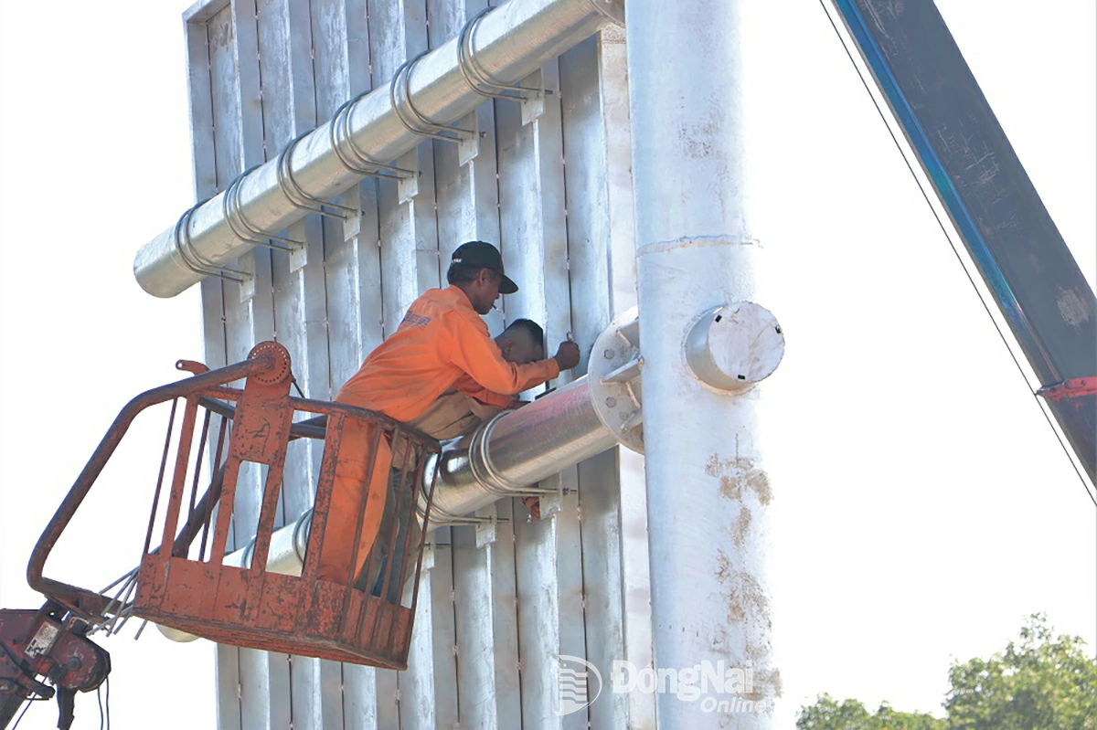 Công nhân thi công lắp đặt hệ thống biển báo giao thông trên đường vành đai 3 - Thành phố Hồ Chí Minh đoạn qua địa bàn tỉnh. Ảnh: Phạm Tùng