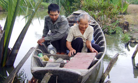 Bà Trần Thị Lắc và người con út vớt ve chai nuôi sống gia đình.  Ảnh: Đ.Hồng