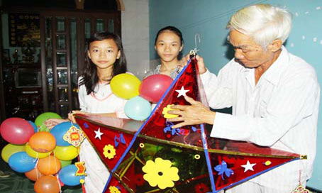 Ông Nguyễn Bá Khuông và 2 cháu gái trang trí Tết Trung thu trước nhà mình.