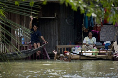Người dân tỉnh Lop Buri ngồi bên ngoài ngôi nhà bị ngập nước