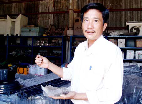 Ông Võ Văn Phụng giới thiệu phụ tùng máy gặt đập liên hợp do DN sản xuất.         Ảnh: B.N