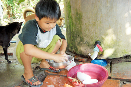 Sau bữa ăn, Anh Tú rửa chén để cha và dì đi làm.                            Ảnh: N. Tuyết