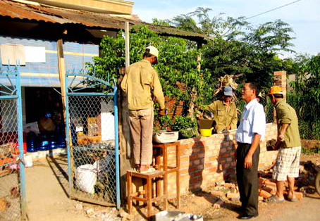 Chủ tịch UBND xã Phạm Ngọc Tâm thăm hỏi những gia đình xây mới tường rào nhà. Ảnh: T.N