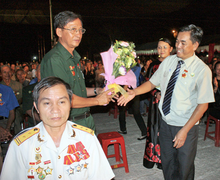 Đồng chí Huỳnh Văn Tới (phải), UV Ban TVTU, Trưởng ban Tuyên giáo Tỉnh ủy tặng hoa chúc mừng đại biểu cựu thanh niên xung phong tham dự chương trình họp mặt tại Chiến khu Đ.    Ảnh: T.THÚY