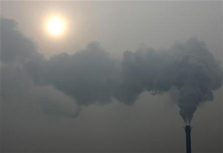 A chimney billows smoke as the sun shines through haze on a cold winter's day in Beijing December 24, 2009. 