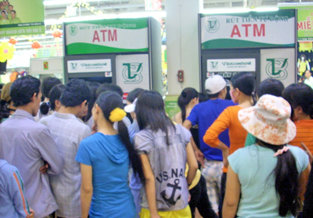 Công nhân chờ rút tiền tại các máy ATM tại siêu thị BigC vào kỳ nhận lương. Ảnh: V. LÂM