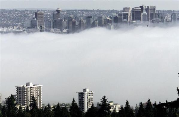 The buildings of downtown Vancouver, Canada (background) and apartment buildings of the North Shore rise above an afternoon fog over ther harbor