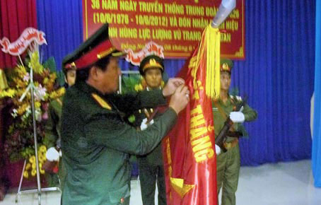 Thiếu tướng Võ Minh Lương gắn danh hiệu Anh hùng lực lượng vũ trang nhân dân lên Quân kỳ quyết thắng của Trung đoàn tăng thiết giáp 26.    Ảnh: Đ. V