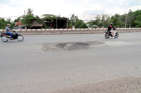 Ban ngày, người đi xe máy trên quốc lộ 51 phải tránh chỗ hỏng, nên lấn ra phần đường dành cho ô tô, dễ bị tai nạn giao thông.      Ảnh: T. Toàn