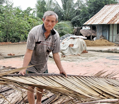 Ông Nguyễn Văn Thanh ở ấp Vĩnh Tuy, xã Long Tân (huyện Nhơn Trạch) chuẩn bị lá dừa lợp lại mái nhà nhiều năm xuống cấp nhưng do vướng quy hoạch nên không được sửa chữa. ẢNH: H.Giang