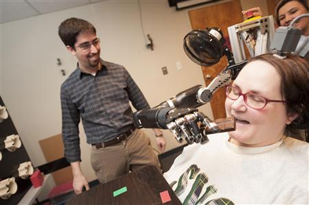 An undated photo shows a 52 year-old woman, paralysed from the neck down, demonstrating the use of a new mind-controlled prosthetic arm with intuitive control to help her eat a chocolate bar at the University of Pittsburgh Medical Centre in Pittsburgh. 