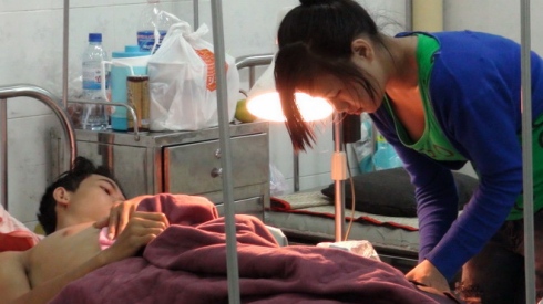 Nguyen Tien Dinh being taken cared of by his wife at the hospital