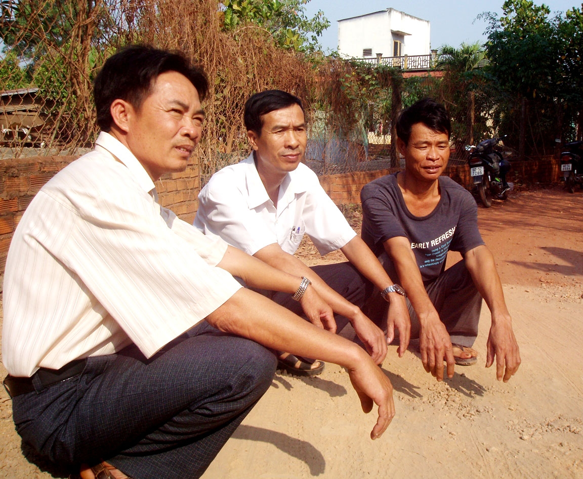 Hai ông Nguyễn Huy Hạnh (trái) và Nguyễn Văn Long (giữa) đang bàn việc làm đường với bà con. Ảnh: T.Nhân