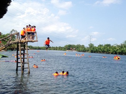 Visitors jump from a wooden ladder at Bo Cap Vang Eco-tourism Area in Dong Nai Province