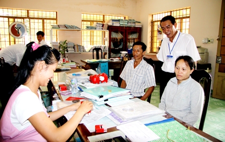 Bí thư Đảng ủy xã Phước An (huyện Nhơn Trạch) Châu Phước Thuận (đứng) đôn đốc cán bộ giải quyết thủ tục cho người dân. Ảnh: CÔNG NGHĨA