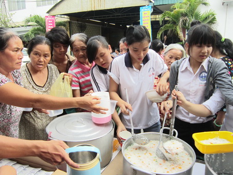 Các em học sinh đang phát cháo cho người nhà bệnh nhân nghèo