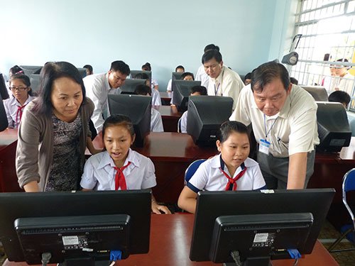 Representatives of STF and PepsiCo Vietnam look at students of Phuoc Thai Secondary School practicing on computers