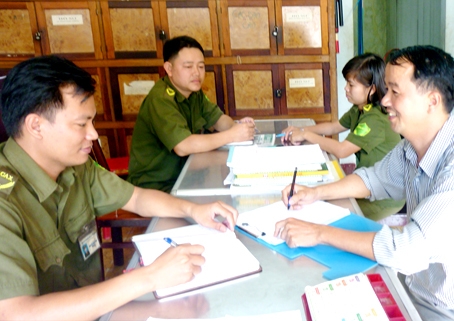 Anh Hà Duy Linh (bìa phải) báo cáo tình hình bảo vệ an ninh trật tự trong ấp với Công an xã Quảng Tiến.