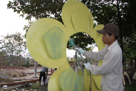 Công nhân phun sơn màu vàng lên cánh hoa mai.