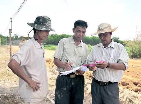 Ông Nguyễn Vinh (bìa trái) cùng kiểm tra sổ sách ghi số lượng đất đã đổ.