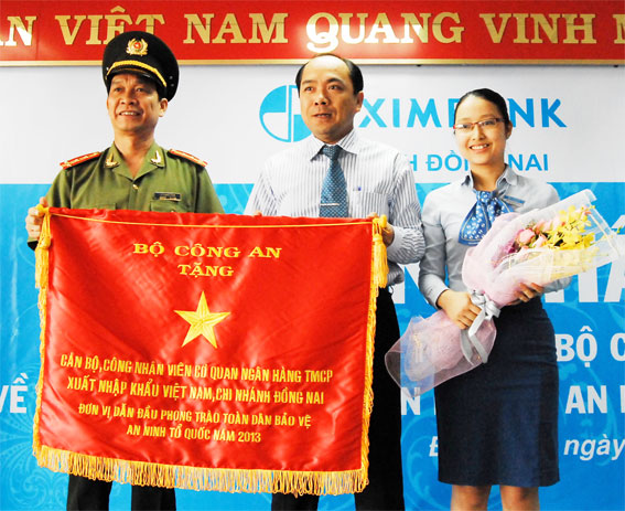 Ông Lý Quang Dũng, Phó giám đốc Công an tỉnh Đồng Nai (trái) trao cờ thi đua của Bộ công an cho đại diện Ngân hàng Eximbank Đồng Nai.  