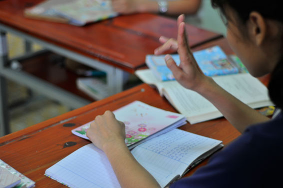 Một bé học lớp 7 khiếm thính đang tranh thủ ôn lại bài trước giờ vào lớp.