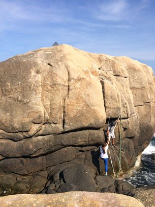 Two people climb by rope to get to the Doi Cape stele