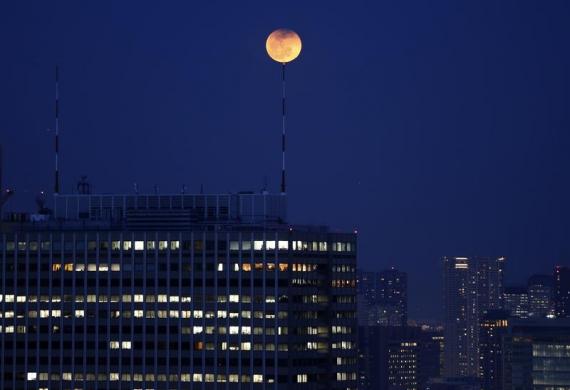 The partial lunar eclipse is seen atop an antenna installed on the roof of a high-rise building in Tokyo April 15, 2014