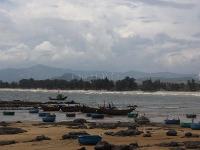 A panoramic view of a fishing village with a wind park in the background