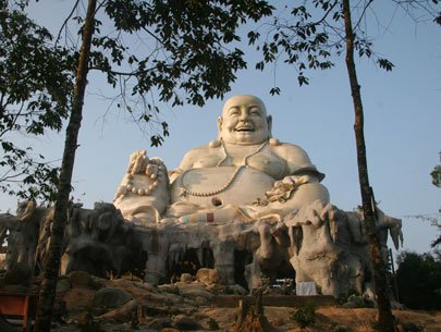 The highest Happy Buddha statue on Cam Mountain. The seven-storey Van Linh Pagoda is viewed in the sunset 