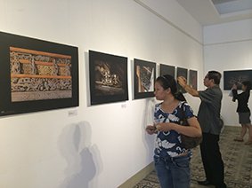 Visitors look at photos of the dragons and fairies carved on 40 communal houses in northern Vietnam at the HCMC Fine Arts Museum - Photo: My Tran 