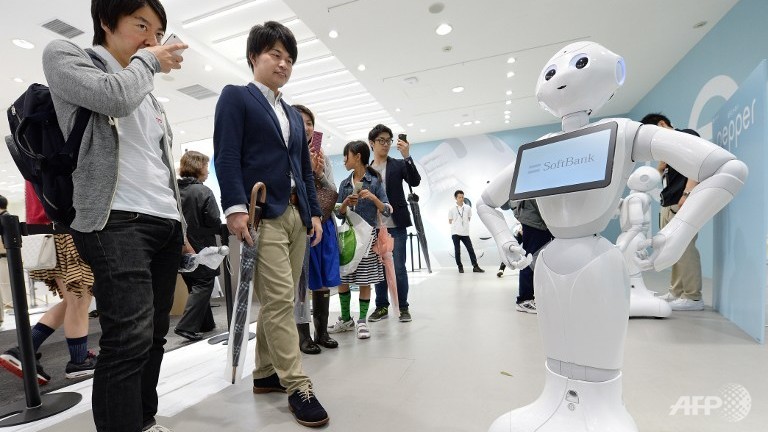 People look at humanoid robot 'Pepper', which is jointly developed by Japan's mobile carrier SoftBank and French humanoid robot maker Alderbaran, in Tokyo. 