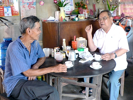 Ông Đỗ Văn Cho (phải) trao đổi cùng một hộ gia đình sống dọc theo  đường liên xã Hưng Lộc - xã Lộ 25.